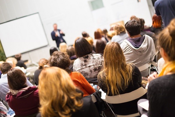 Speaker Giving a Talk at Business Meeting. Audience in the conference hall. Business and Entrepreneurship. Copy space on white board.